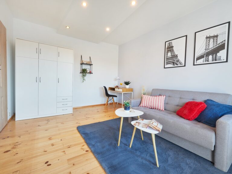 Pokój z balkonem i szarą sofą, ul. Osmeckiego 33, Rzeszów. Niezłe Lokum urządziło przestrzeń, dodając akcenty paryskie na ścianie i tworząc miejsce do relaksu i pracy.