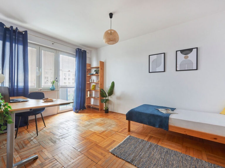 Duża sypialnia z drzwiami na balkon, ul. Popiełuszki 6, Rzeszów. Niezłe Lokum wykorzystało potencjał istniejącego wyposażenia, takiego jak łóżko, biurko i drewniane półki.